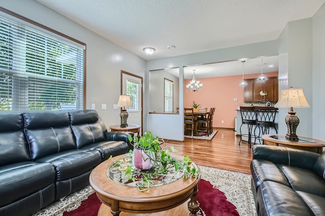 living room featuring hardwood / wood-style floors, a textured ceiling, and a notable chandelier