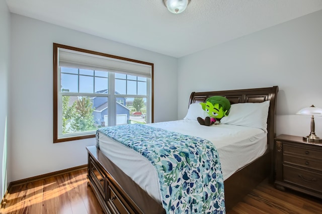 bedroom featuring baseboards and dark wood-style flooring