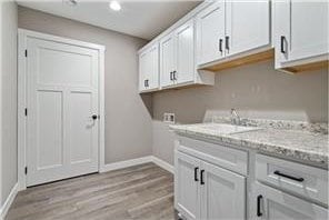 washroom featuring sink, light hardwood / wood-style floors, hookup for a washing machine, and cabinets