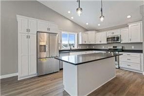 745 Hilltop Ln, Saint Croix Falls, WI 54024 - kitchen with stainless steel appliances, lofted ceiling, dark countertops, white cabinets, and dark wood-style floors