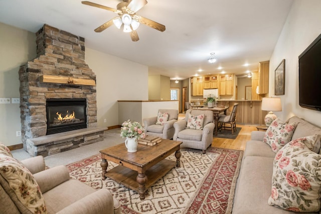 living room featuring ceiling fan, a fireplace, and light hardwood / wood-style floors