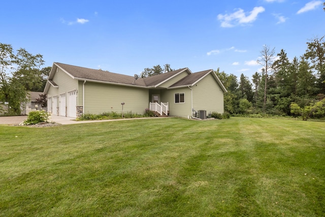 view of front of property with a garage, a front yard, and central AC