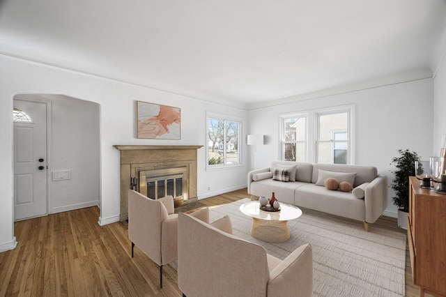 living area with baseboards, a fireplace with flush hearth, and wood finished floors