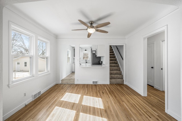 unfurnished living room featuring visible vents, light wood-style floors, and stairs