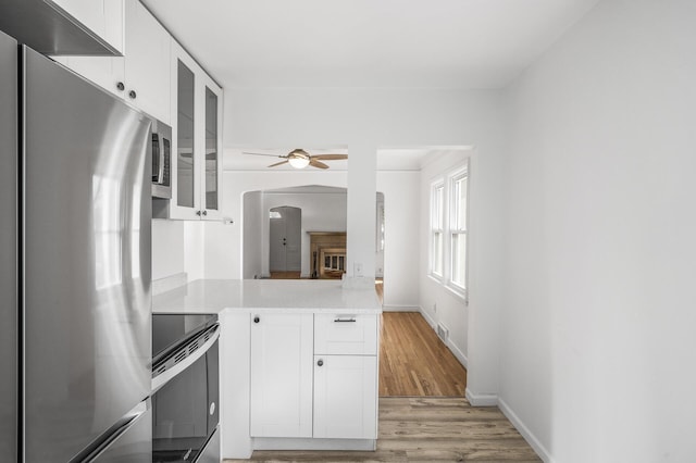 kitchen with light countertops, white cabinets, electric stove, and freestanding refrigerator