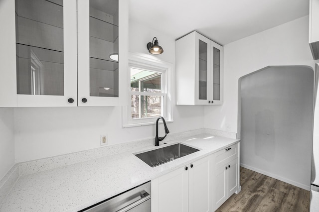 kitchen featuring light stone counters, white cabinetry, glass insert cabinets, and a sink