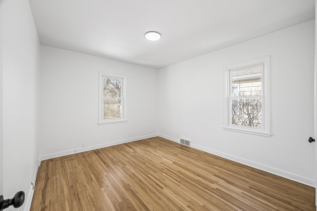 unfurnished room featuring light wood-style floors, visible vents, and baseboards