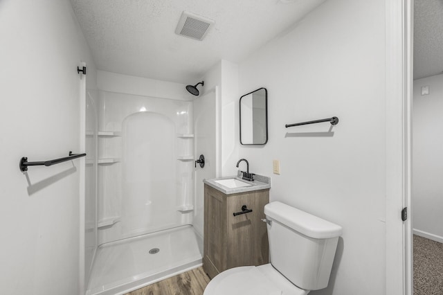 bathroom featuring a shower, visible vents, toilet, and a textured ceiling