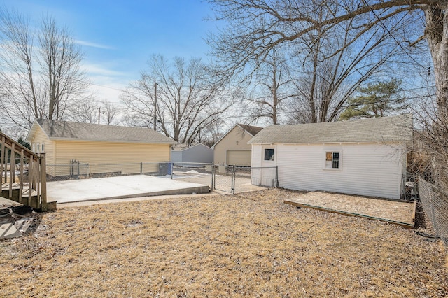 view of yard with a gate, fence, an outdoor structure, a garage, and a patio area