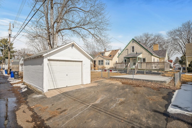 view of front facade featuring a deck, driveway, fence, an outdoor structure, and a garage