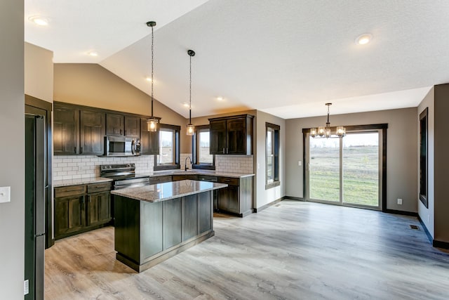 kitchen featuring light stone countertops, a center island, stainless steel appliances, and plenty of natural light