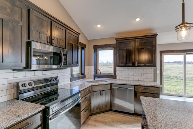 kitchen with appliances with stainless steel finishes, vaulted ceiling, a healthy amount of sunlight, and sink