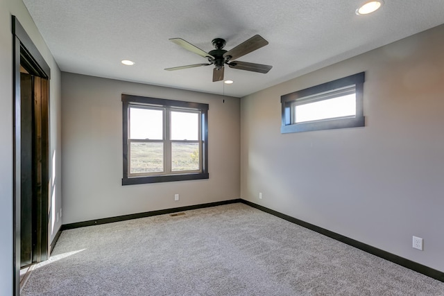 carpeted empty room featuring ceiling fan and a textured ceiling