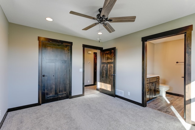 unfurnished bedroom featuring ensuite bathroom, ceiling fan, and light colored carpet