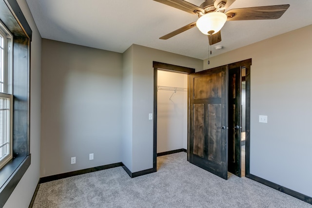 unfurnished bedroom with ceiling fan, a closet, light colored carpet, and multiple windows