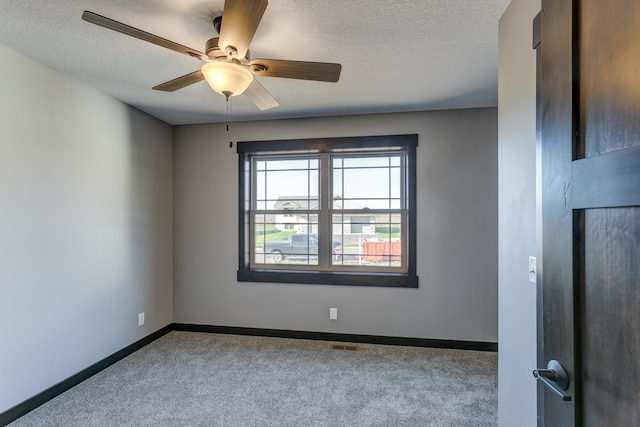 spare room featuring a textured ceiling, light colored carpet, and ceiling fan