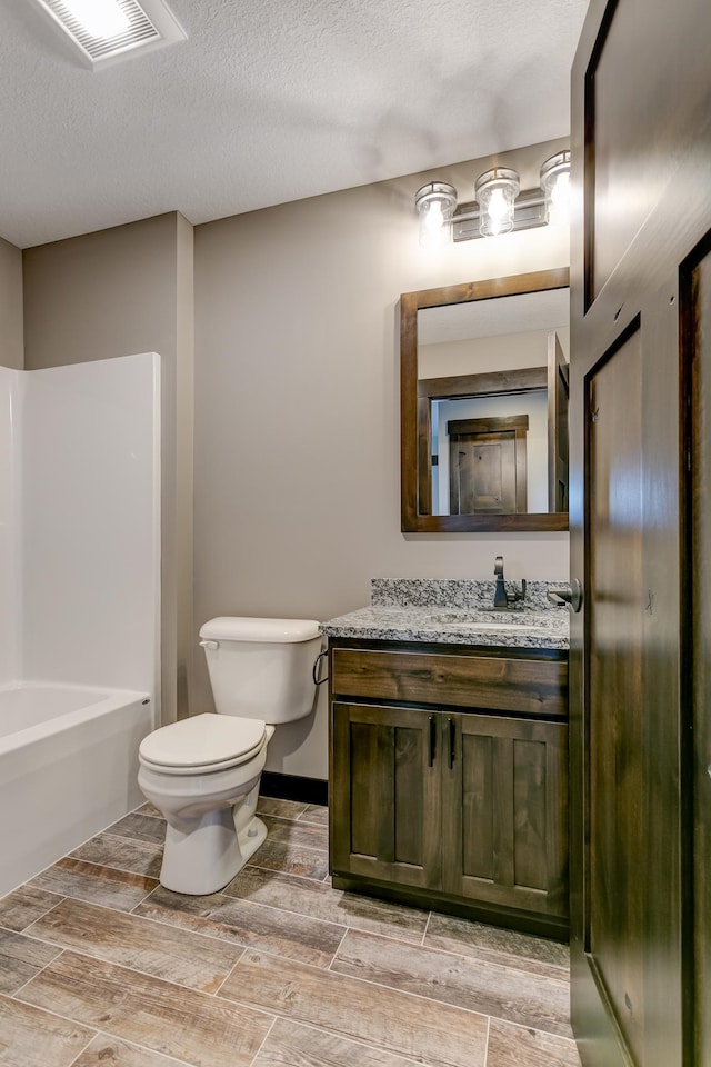 bathroom with vanity, toilet, wood-type flooring, and a textured ceiling