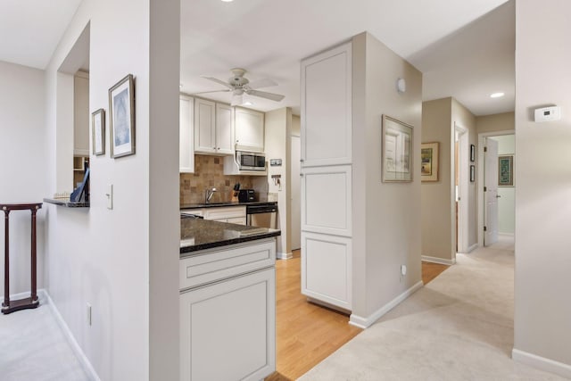 kitchen featuring sink, ceiling fan, appliances with stainless steel finishes, backsplash, and light colored carpet