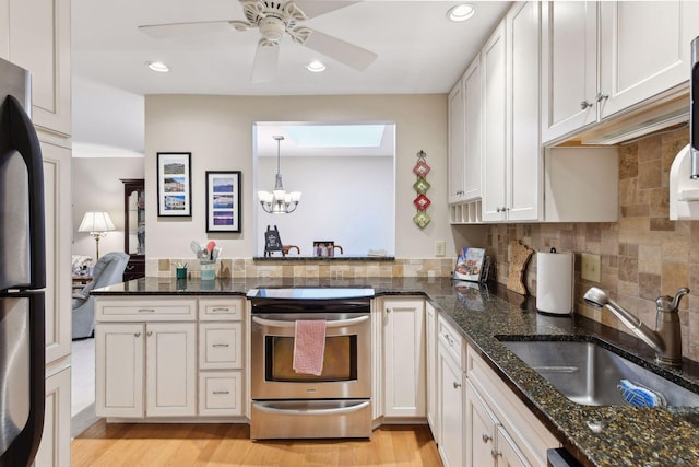 kitchen featuring fridge, white cabinetry, stainless steel electric range oven, and dark stone counters