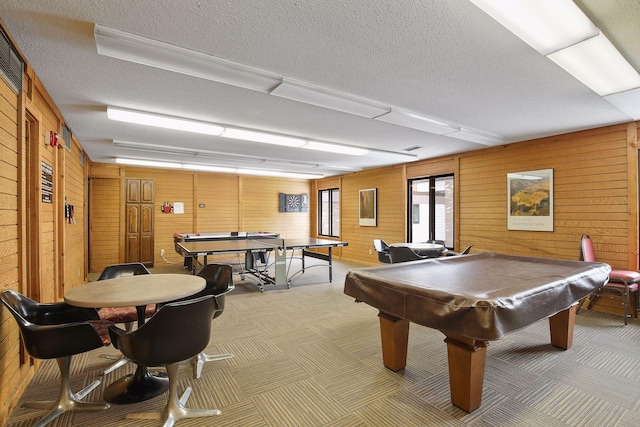 game room featuring pool table, a textured ceiling, and wood walls