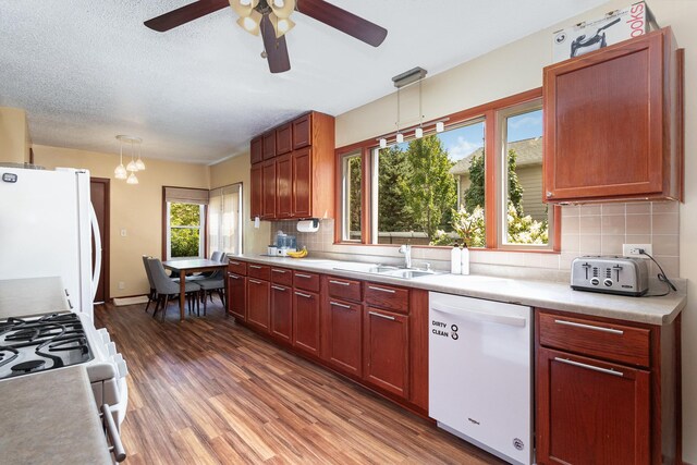 kitchen featuring backsplash, dark hardwood / wood-style floors, sink, white appliances, and hanging light fixtures