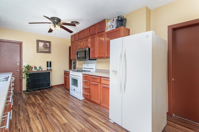 kitchen with a textured ceiling, radiator, white appliances, ceiling fan, and hardwood / wood-style flooring