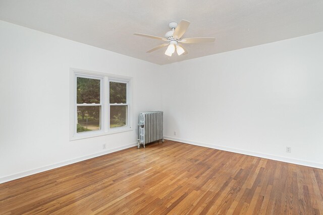 spare room with ceiling fan, light hardwood / wood-style flooring, and radiator