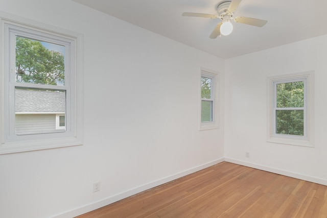 unfurnished room with ceiling fan, a wealth of natural light, and wood-type flooring