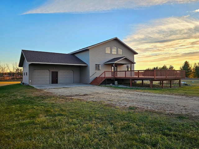 view of front of home featuring a garage, a wooden deck, and a lawn