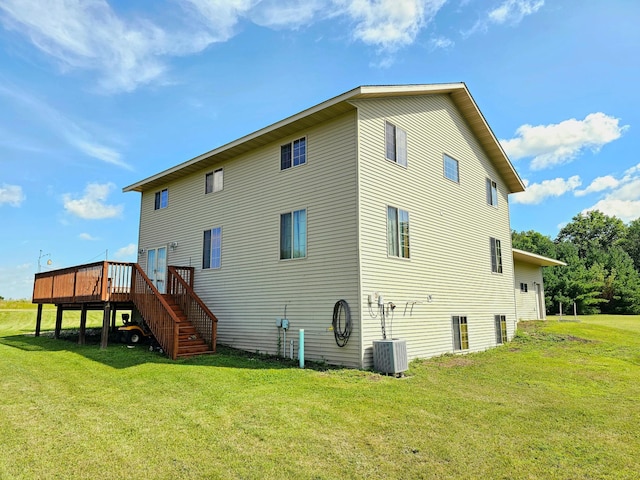 rear view of property featuring a lawn, central AC, and a deck