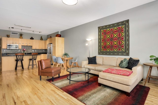 living room with rail lighting and light hardwood / wood-style floors