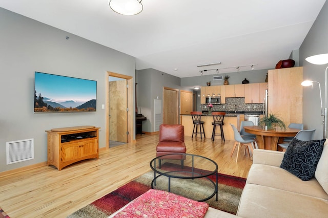 living room with rail lighting and light hardwood / wood-style floors