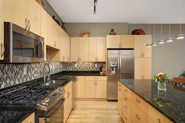 kitchen with appliances with stainless steel finishes, sink, light brown cabinets, and dark stone countertops