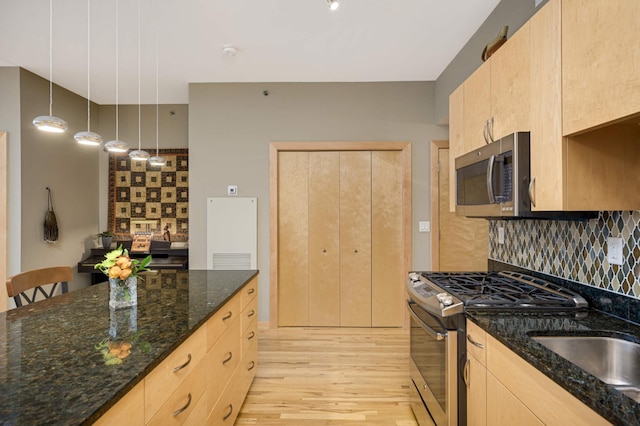 kitchen with stainless steel appliances, decorative backsplash, light brown cabinets, decorative light fixtures, and dark stone counters