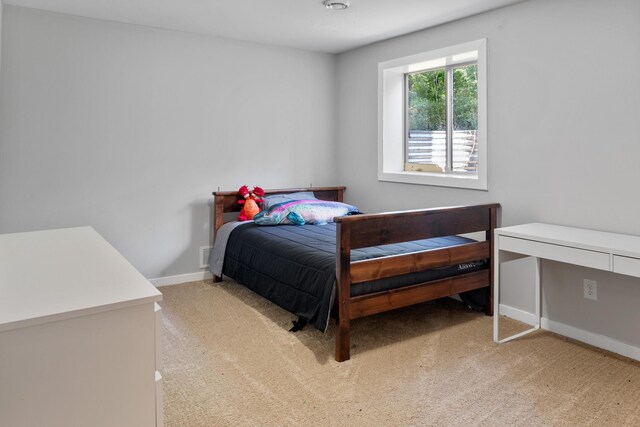 bedroom with baseboards and light carpet