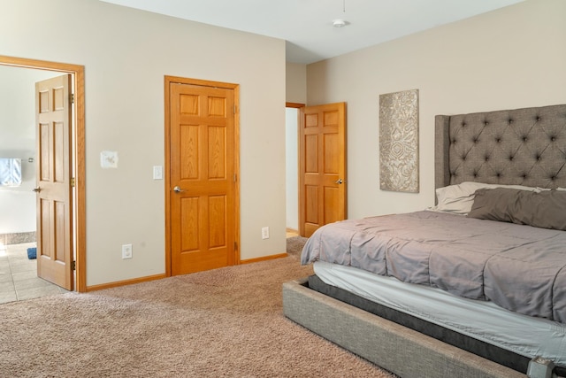 carpeted bedroom featuring ensuite bath and baseboards