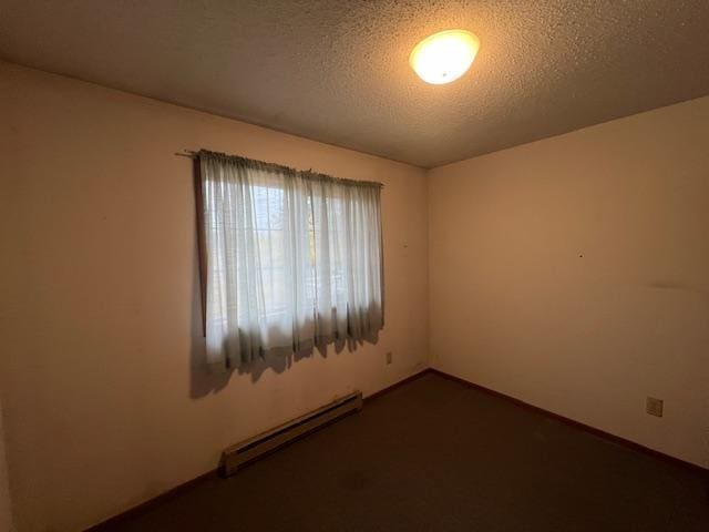 unfurnished room featuring a textured ceiling and baseboard heating