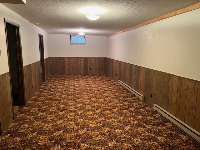 basement featuring a baseboard heating unit and a textured ceiling