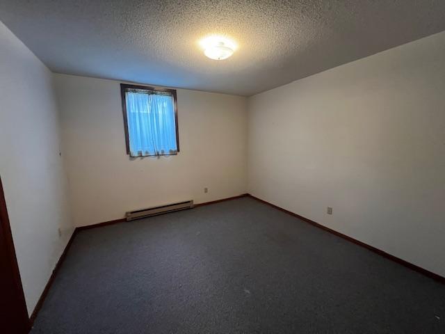 carpeted empty room with baseboard heating and a textured ceiling