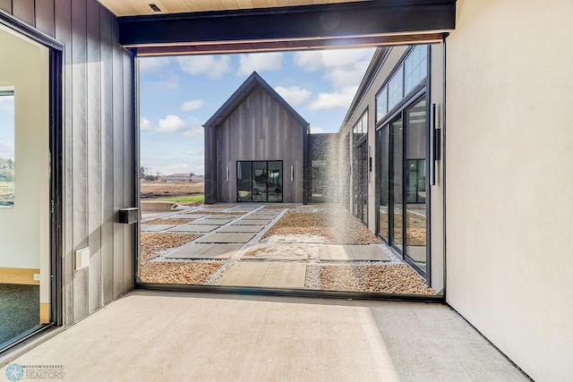 doorway with beamed ceiling and a glass covered fireplace