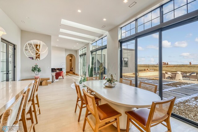 dining space featuring light wood-style flooring, arched walkways, and recessed lighting