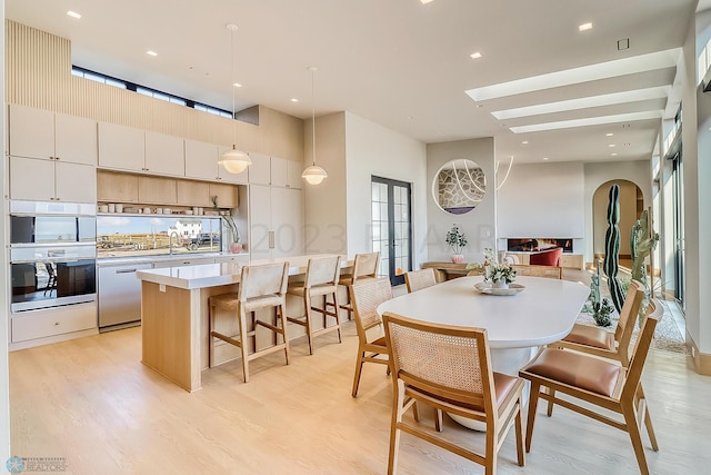 dining room with a wealth of natural light, light wood-style floors, and a skylight