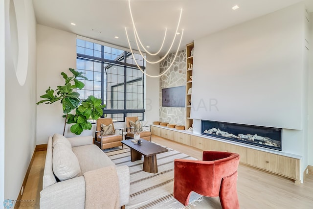 living room with baseboards, recessed lighting, a notable chandelier, and light wood-type flooring