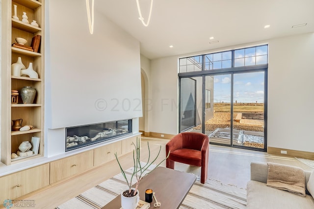 living area featuring arched walkways, baseboards, and built in features
