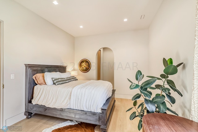 bedroom featuring arched walkways, recessed lighting, and wood finished floors