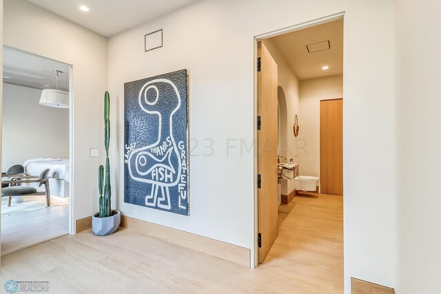 corridor featuring baseboards, arched walkways, and wood finished floors
