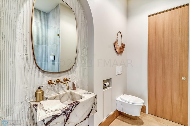 bathroom featuring a sink, toilet, and wood finished floors