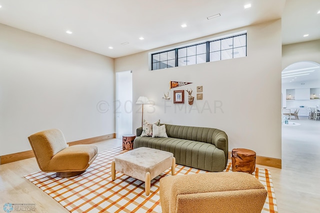 living area featuring light wood-style flooring, baseboards, arched walkways, and recessed lighting