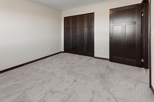 unfurnished bedroom featuring light colored carpet and a closet