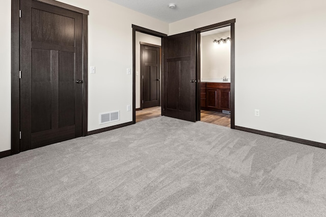 unfurnished bedroom with light colored carpet and ensuite bath